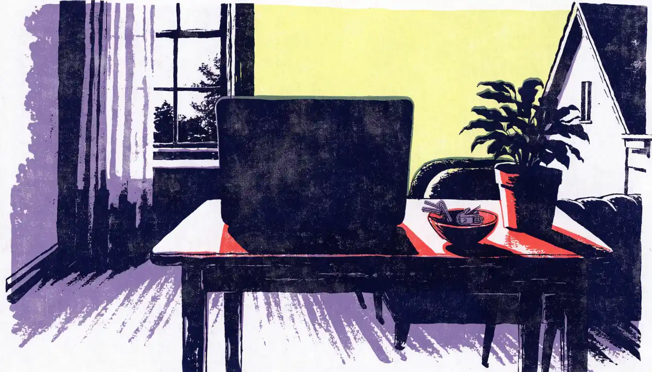 Closed laptop on a wooden desk in a bright British home office with a plant and keys.